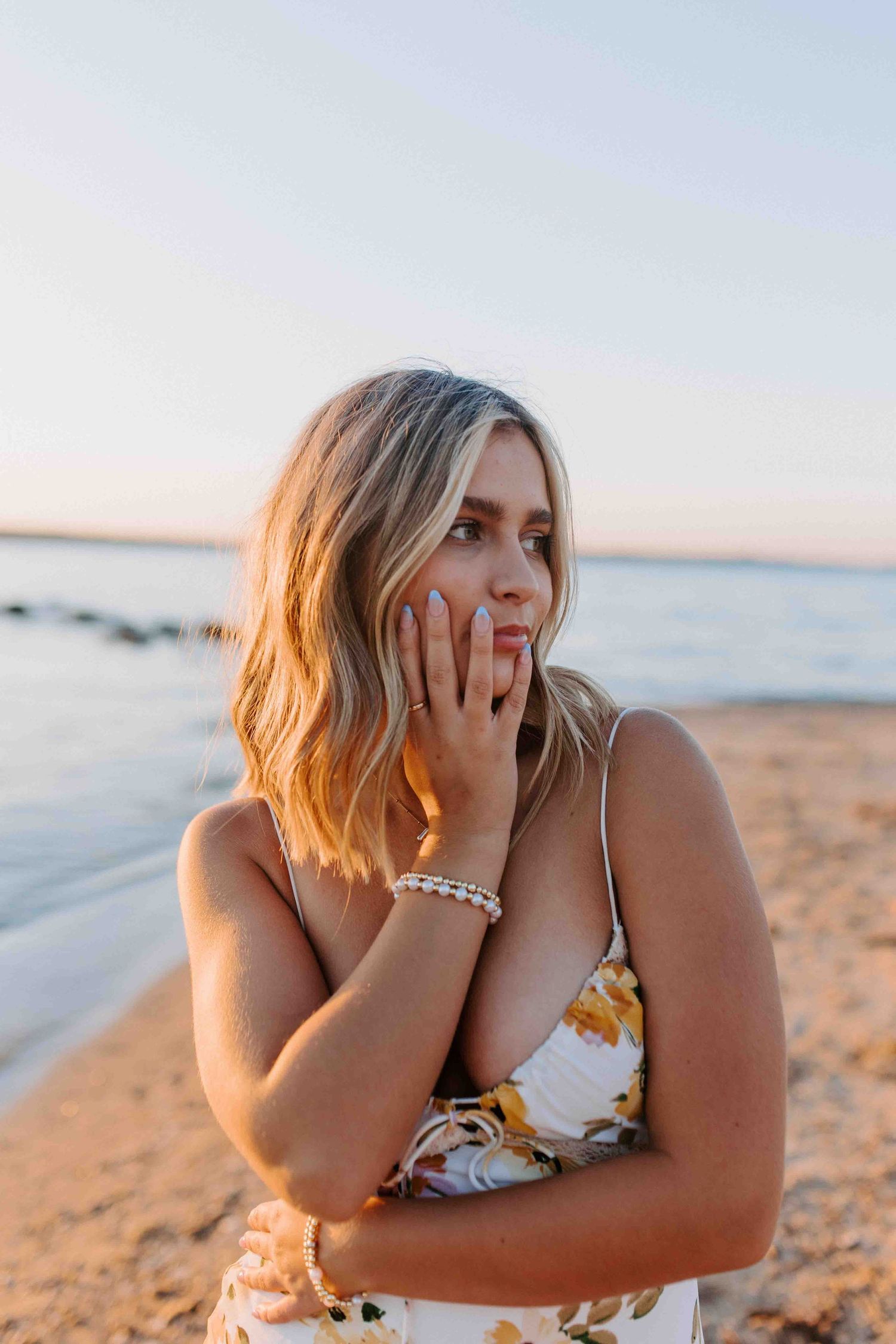 Playful portrait series of woman in floral dress making expressive faces on beach.