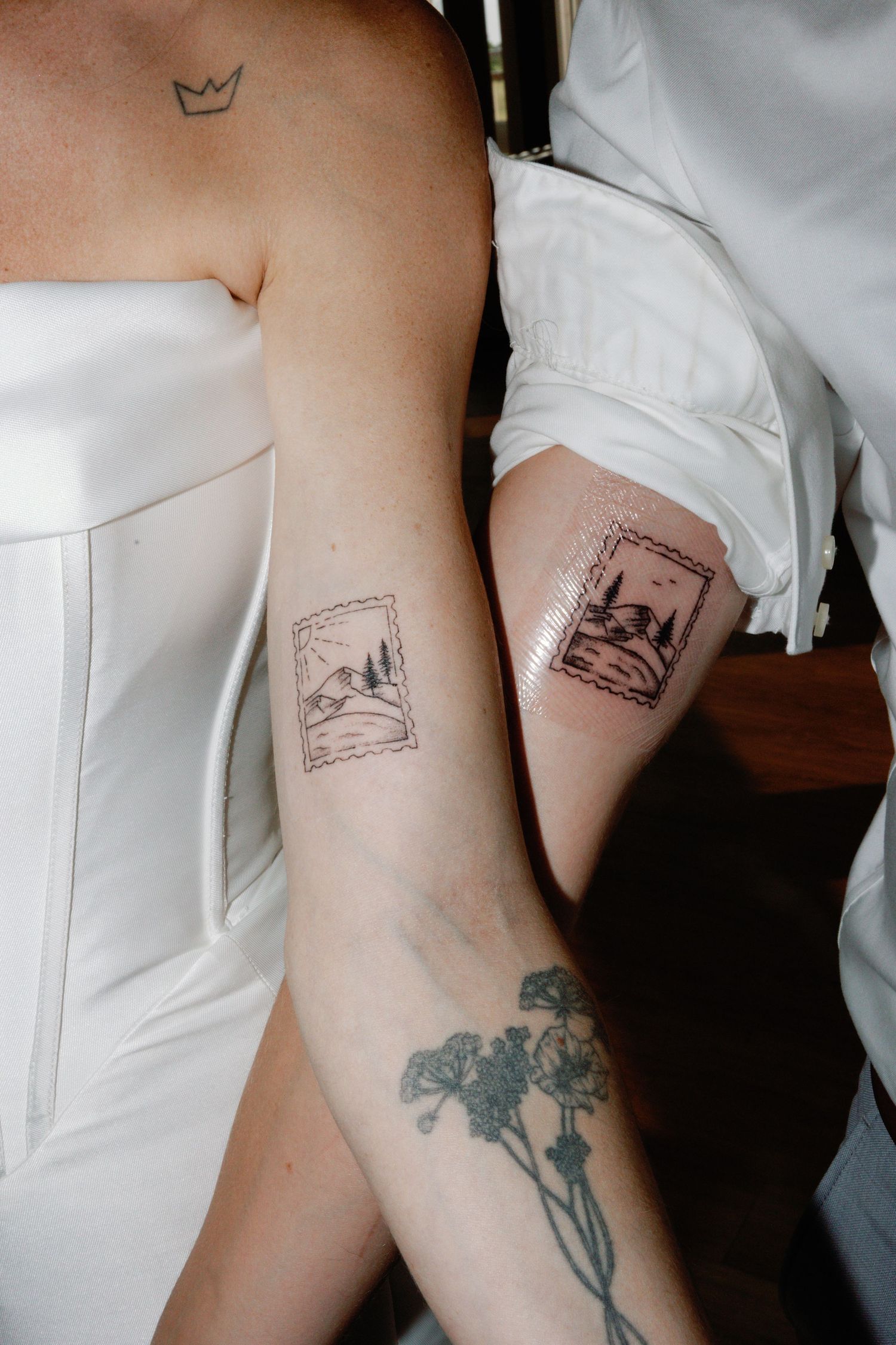 Close-up details of artistic tattoos on someone wearing a white dress.