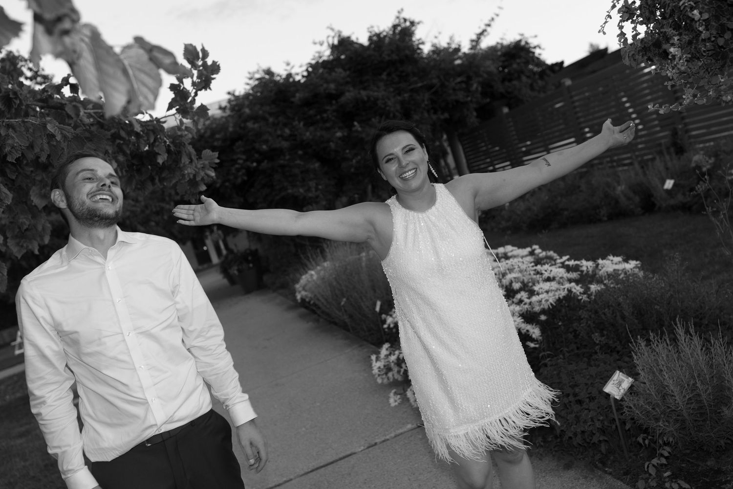 A joyful black and white photo of a couple celebrating outdoors in a garden setting.