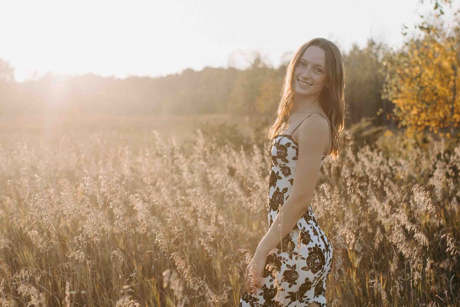 Dreamy autumn photoshoot in a meadow with warm sunset lighting.