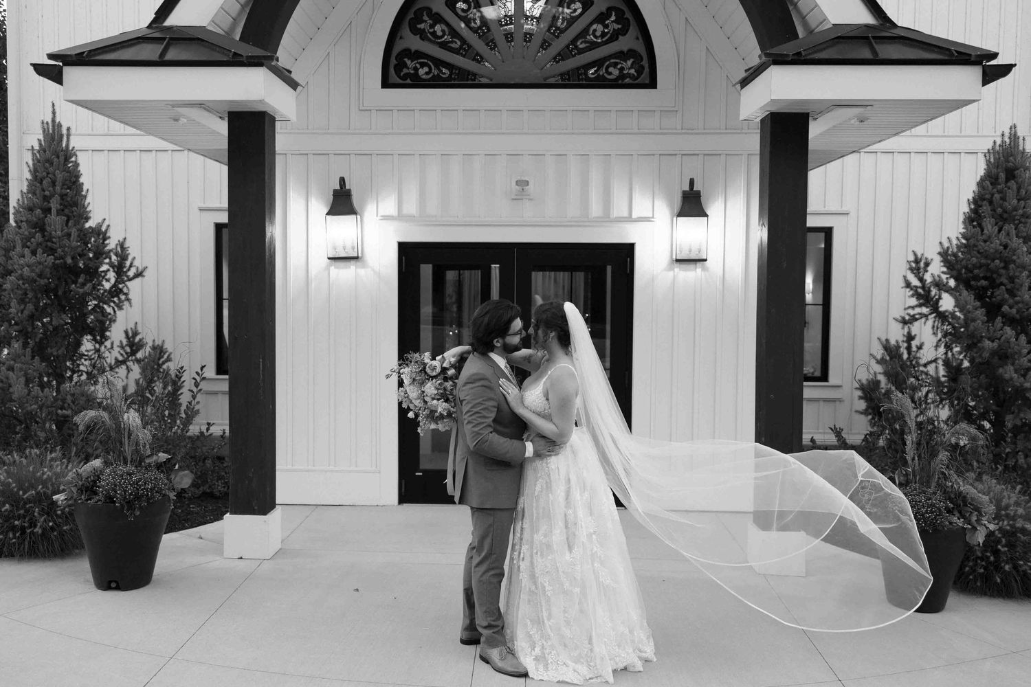 Black and white wedding photos showing couple's romantic moments outside a chapel entrance.