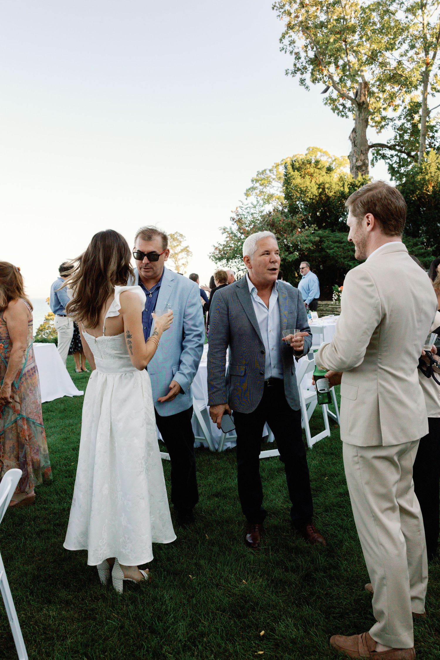 Wedding guests mingle on a lawn during an outdoor summer celebration.