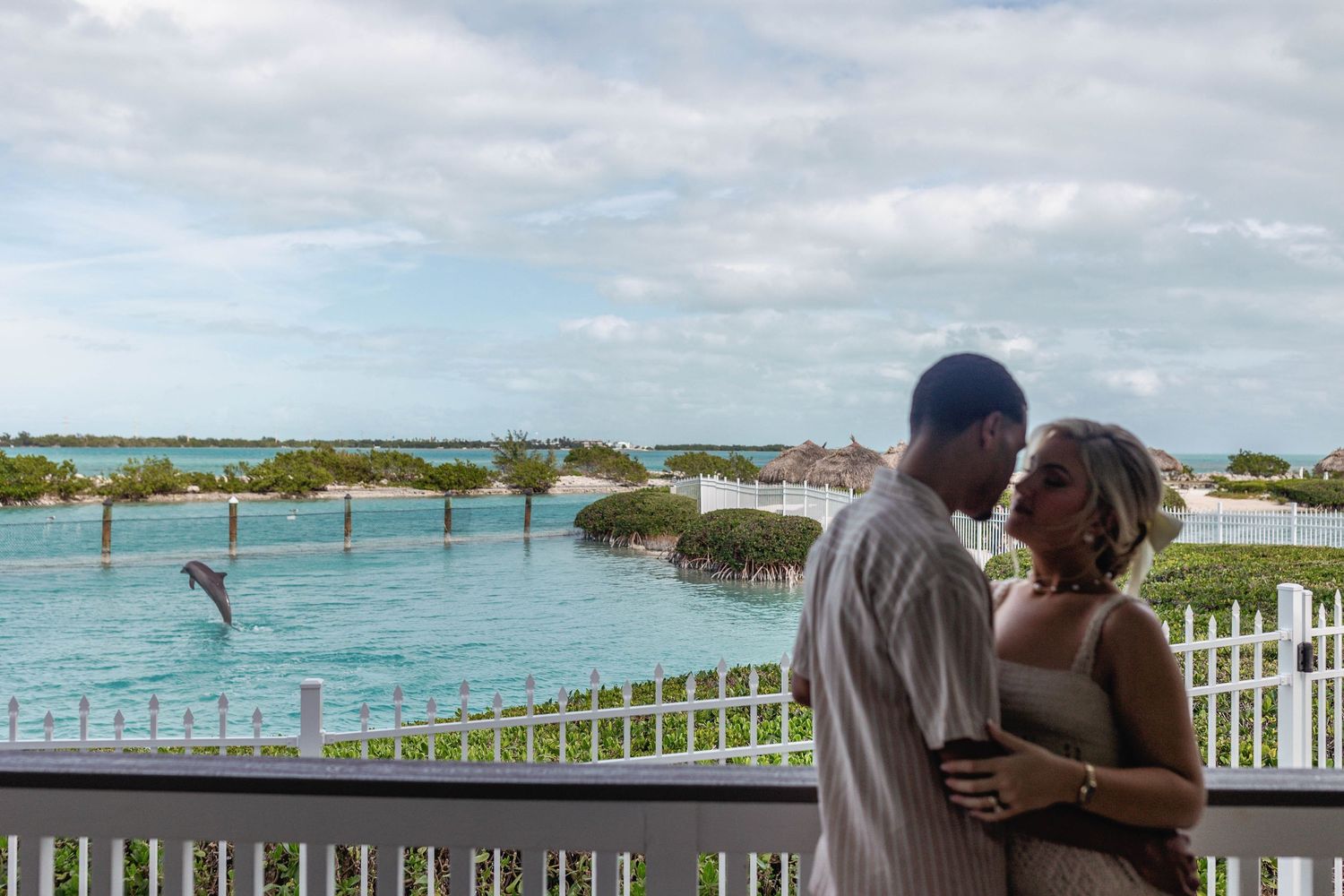 Romantic balcony scene overlooking turquoise waters and tropical landscape.