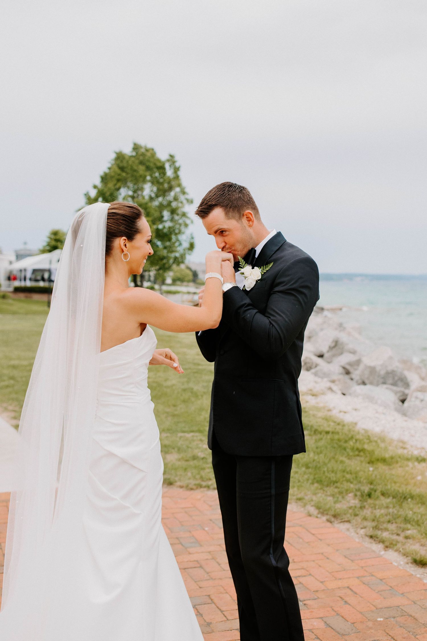 Joyful wedding couple shares playful moment by ocean during photo session.