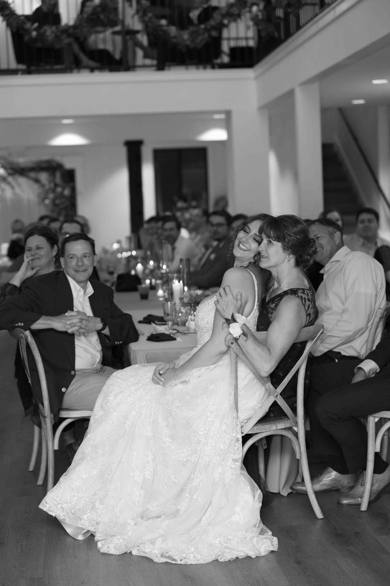 Black and white photo of wedding guests dancing and celebrating at an indoor reception.