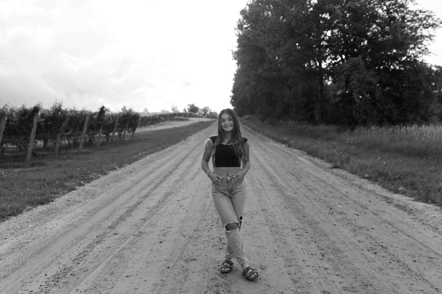 Black and white photograph showing figures walking down a rural country road.