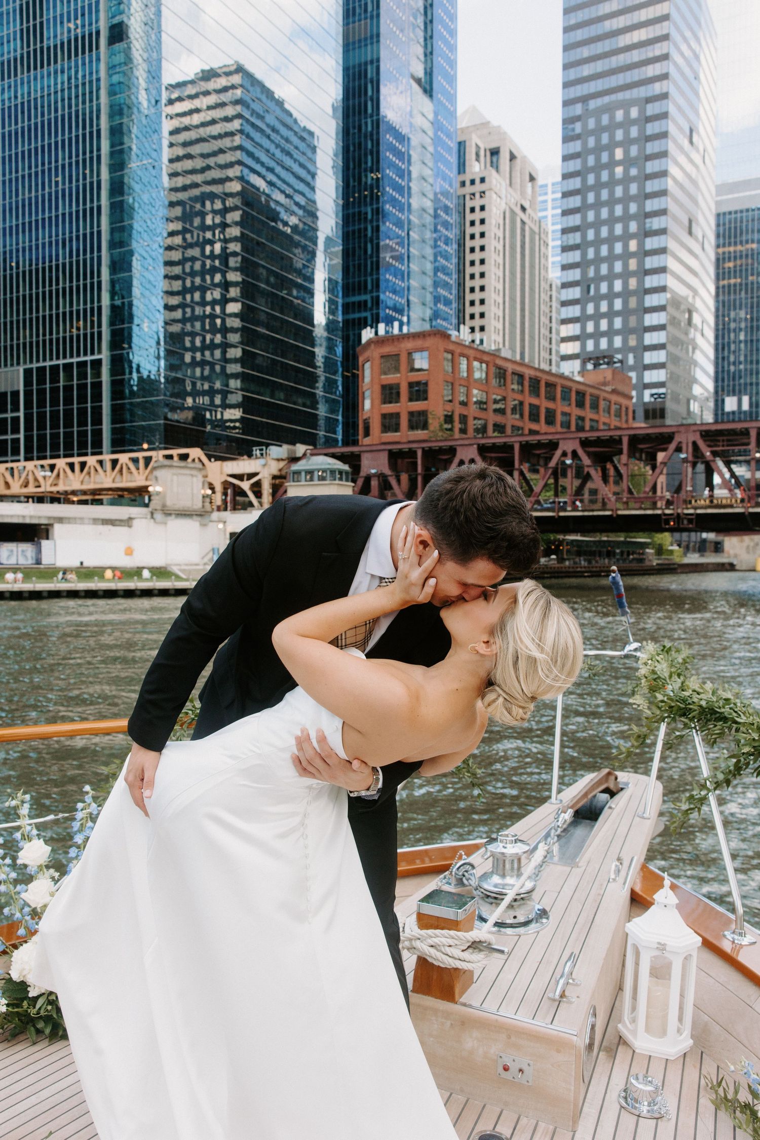 Romantic wedding photos on boat deck with Chicago skyline and bridges in background.
