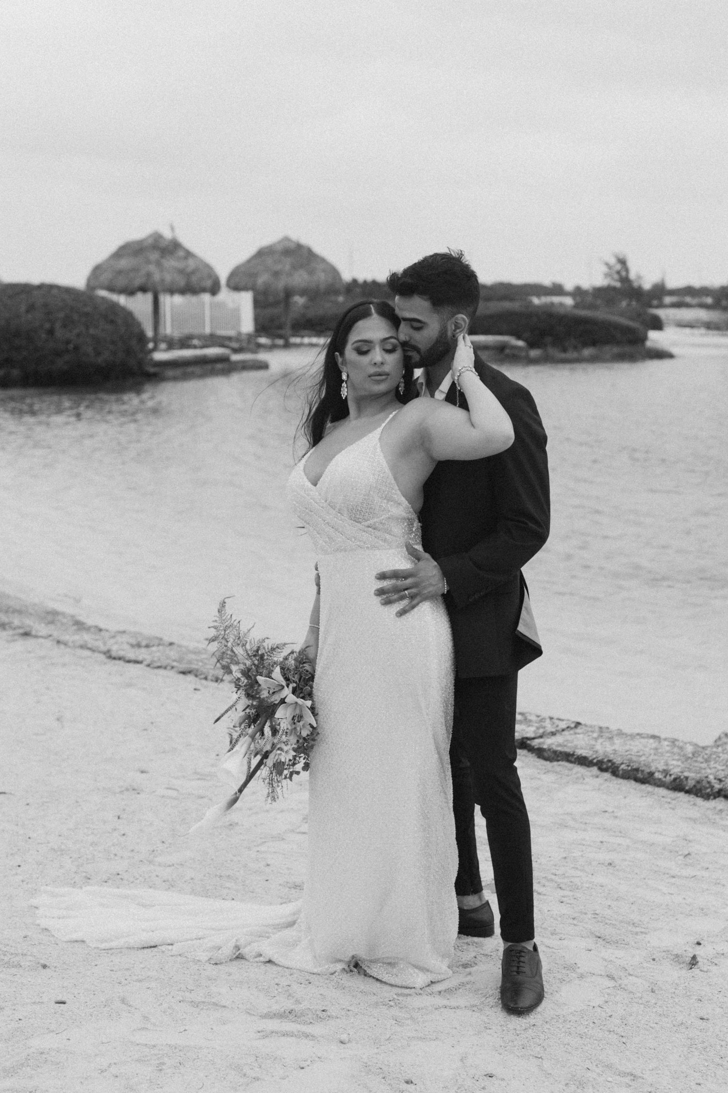 Black and white beach wedding photos showing intimate moments between newlyweds on the shore.