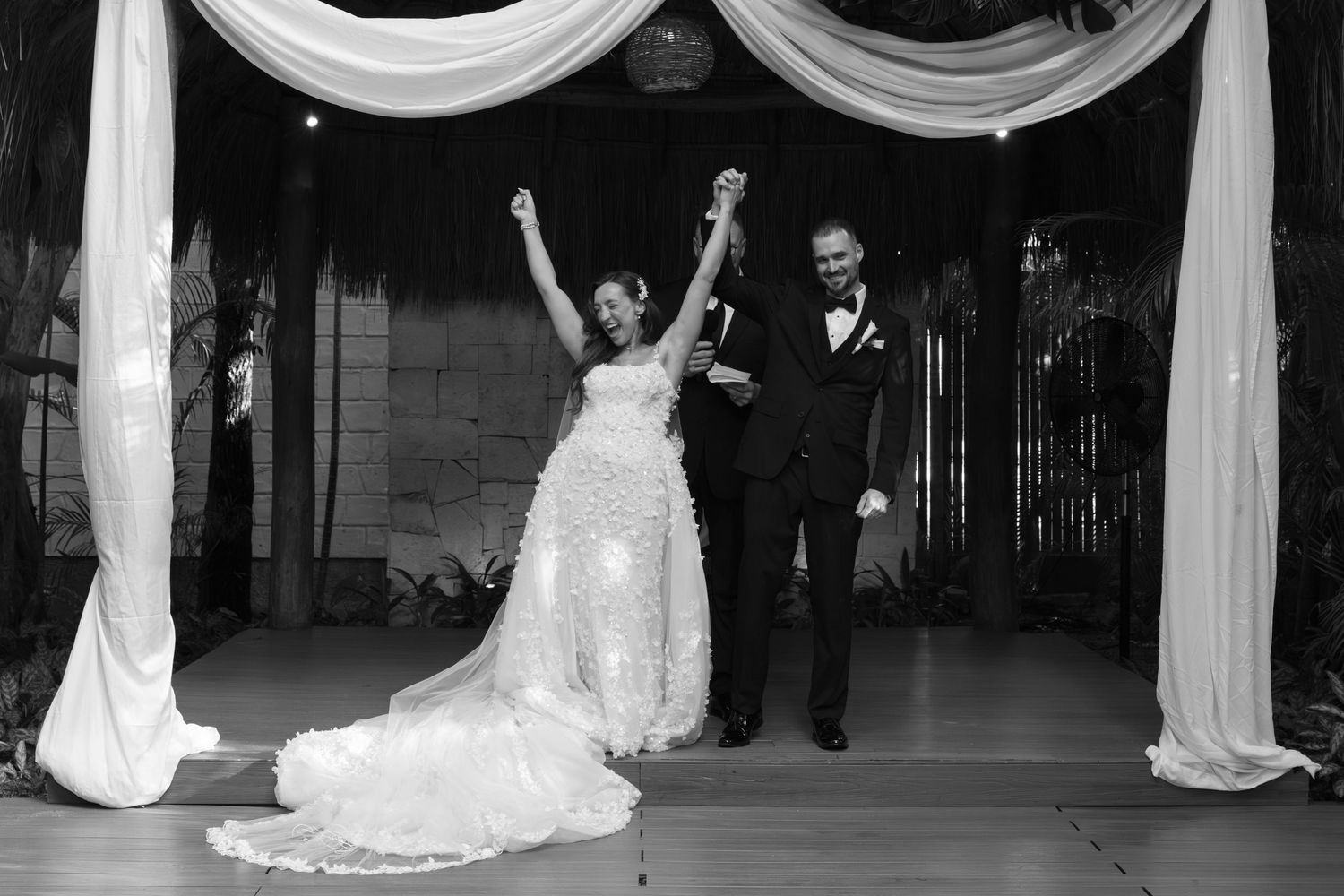 Wedding ceremony setup with white fabric draping and chairs in an elegant indoor venue.