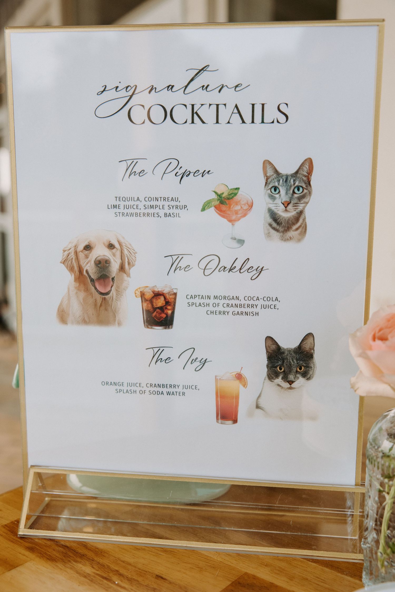 Wedding cocktail menu featuring pet-inspired signature drinks in gold frames.
