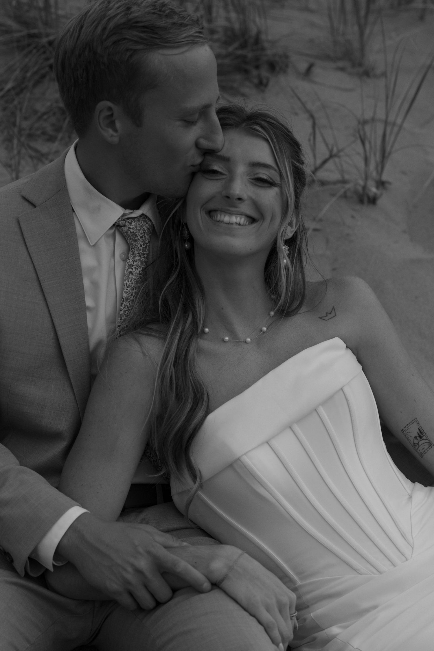 Candid black and white beach wedding portraits showing intimate moments between newlyweds.