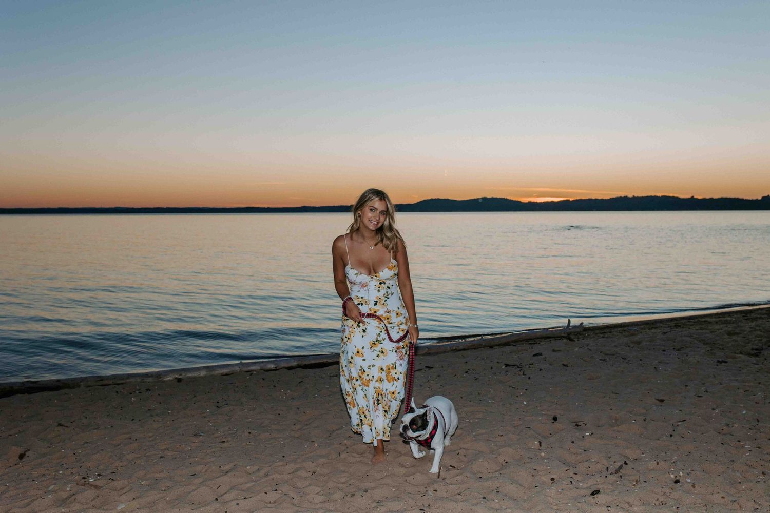 Beachside portrait session at golden hour with calm waters in background.