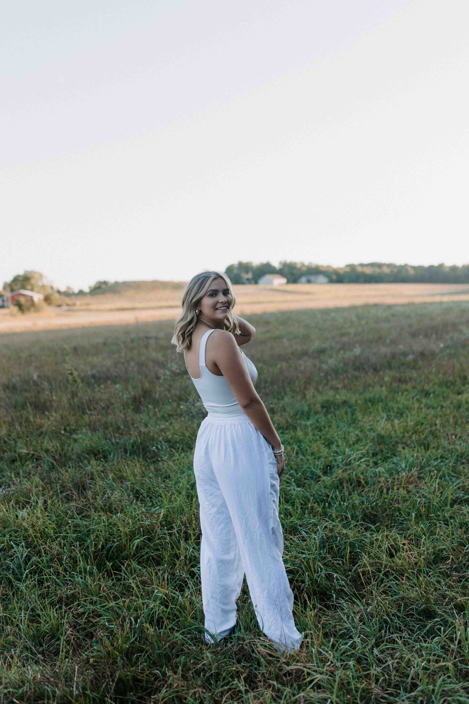 Casual white outfit portrait session in a green field during golden hour.