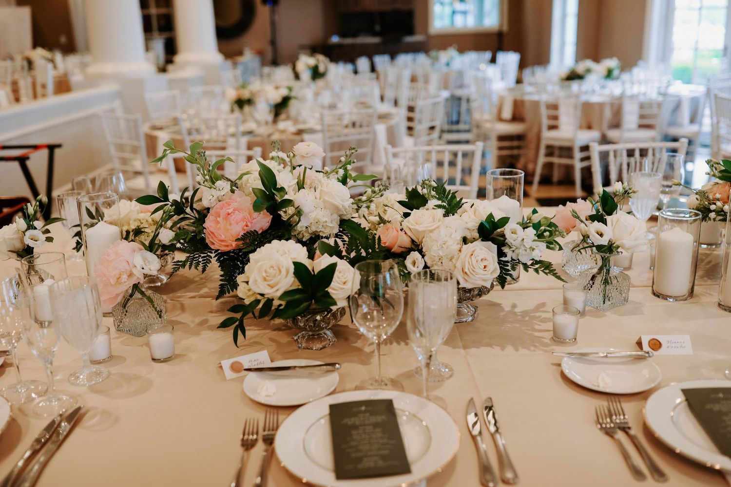 An elegant table setting with lush pink and white floral arrangements and formal place settings.