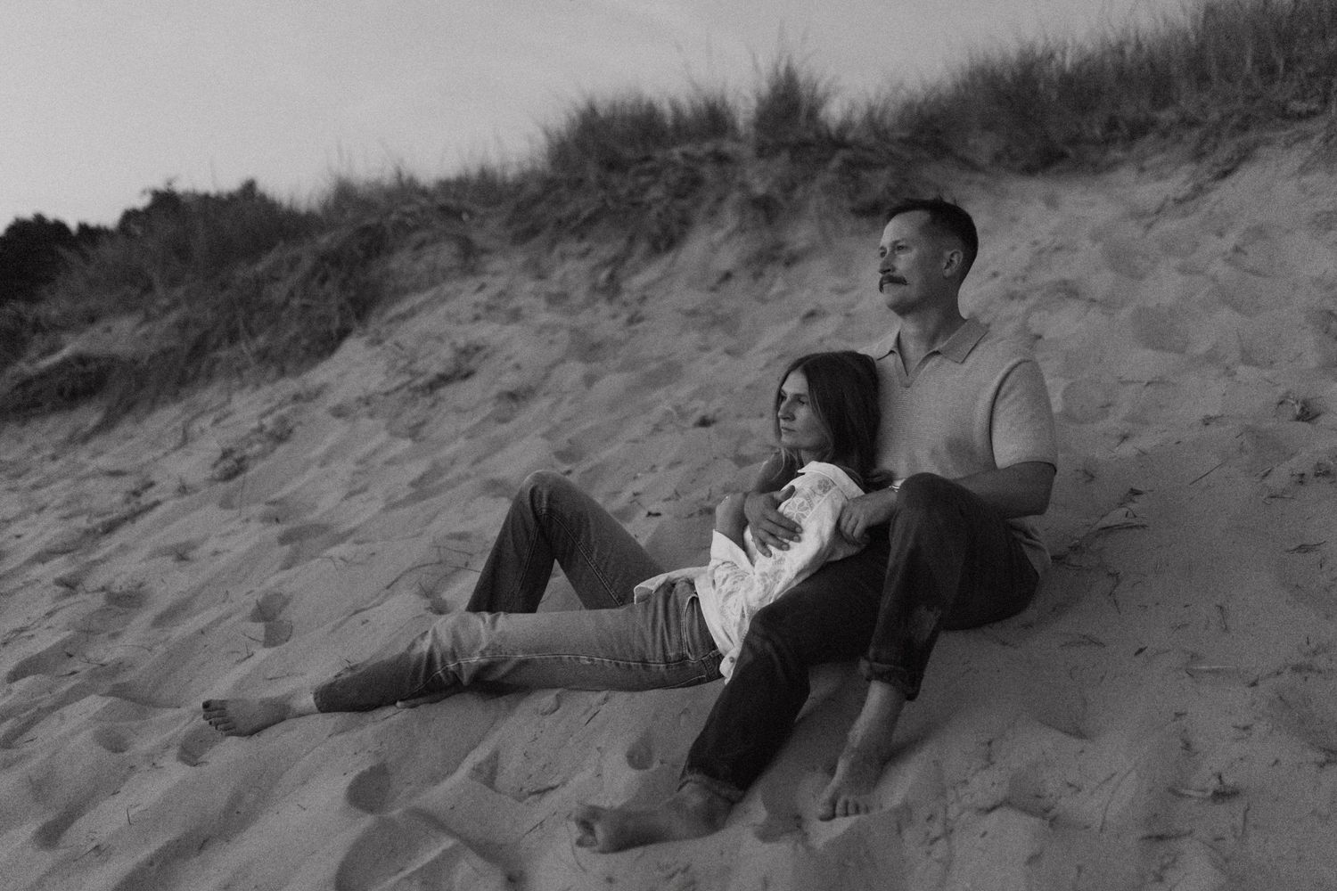 Couple lying together on sandy dunes at twilight.