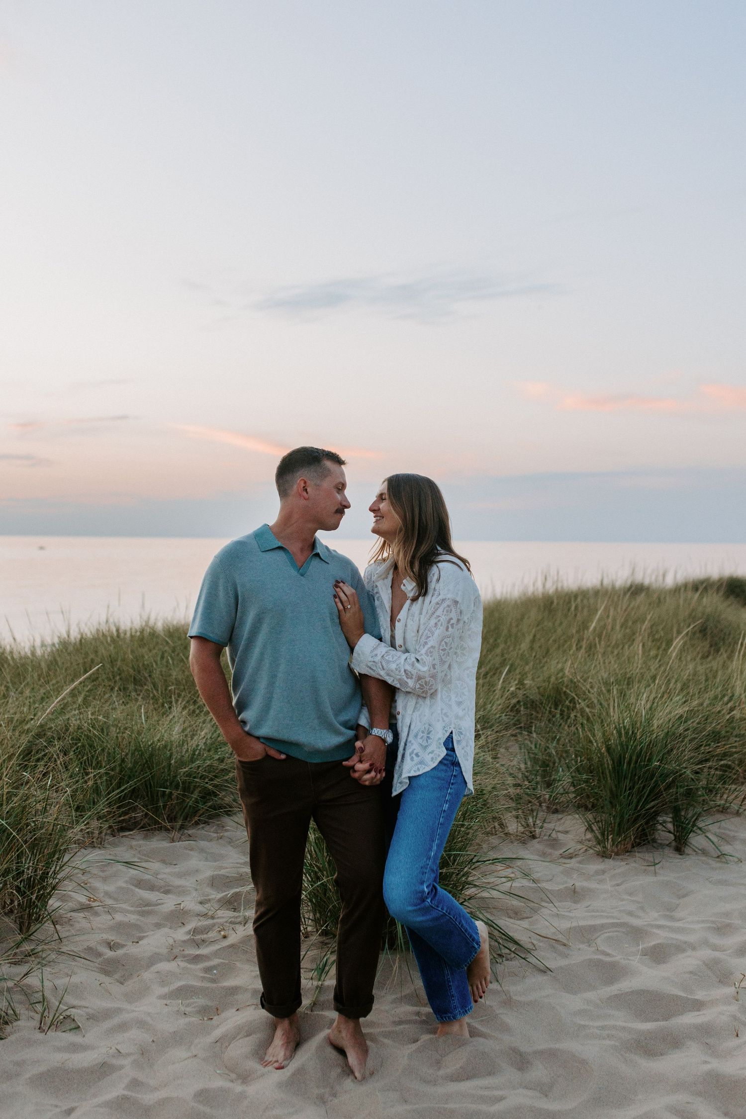 A couple enjoying playful moments together on a sandy beach at dusk.