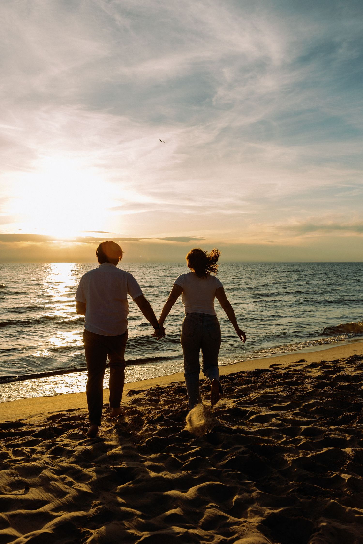 Silhouettes of a couple walking along the beach at sunset.