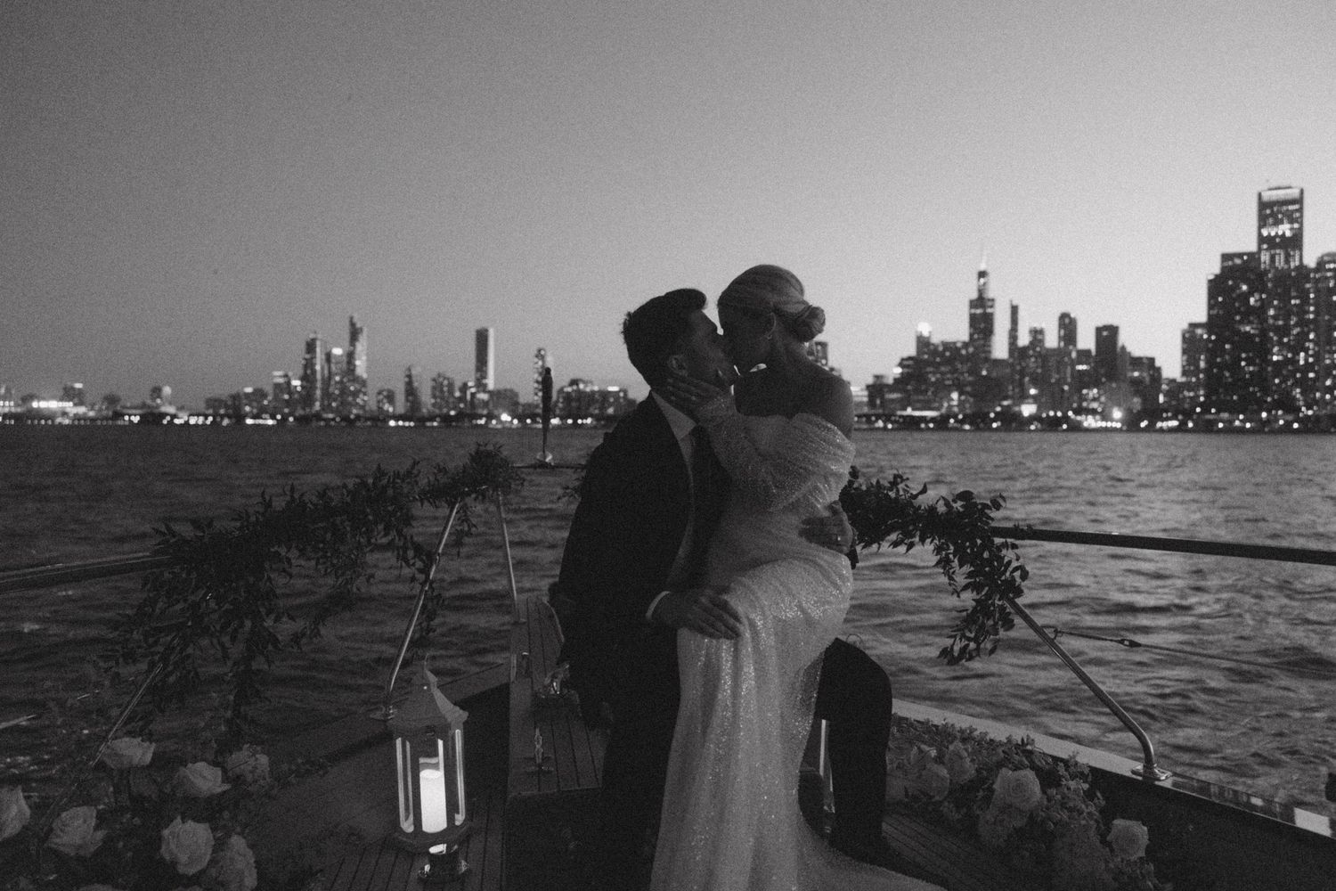 Evening boat wedding reception setup with lanterns and skyline views.