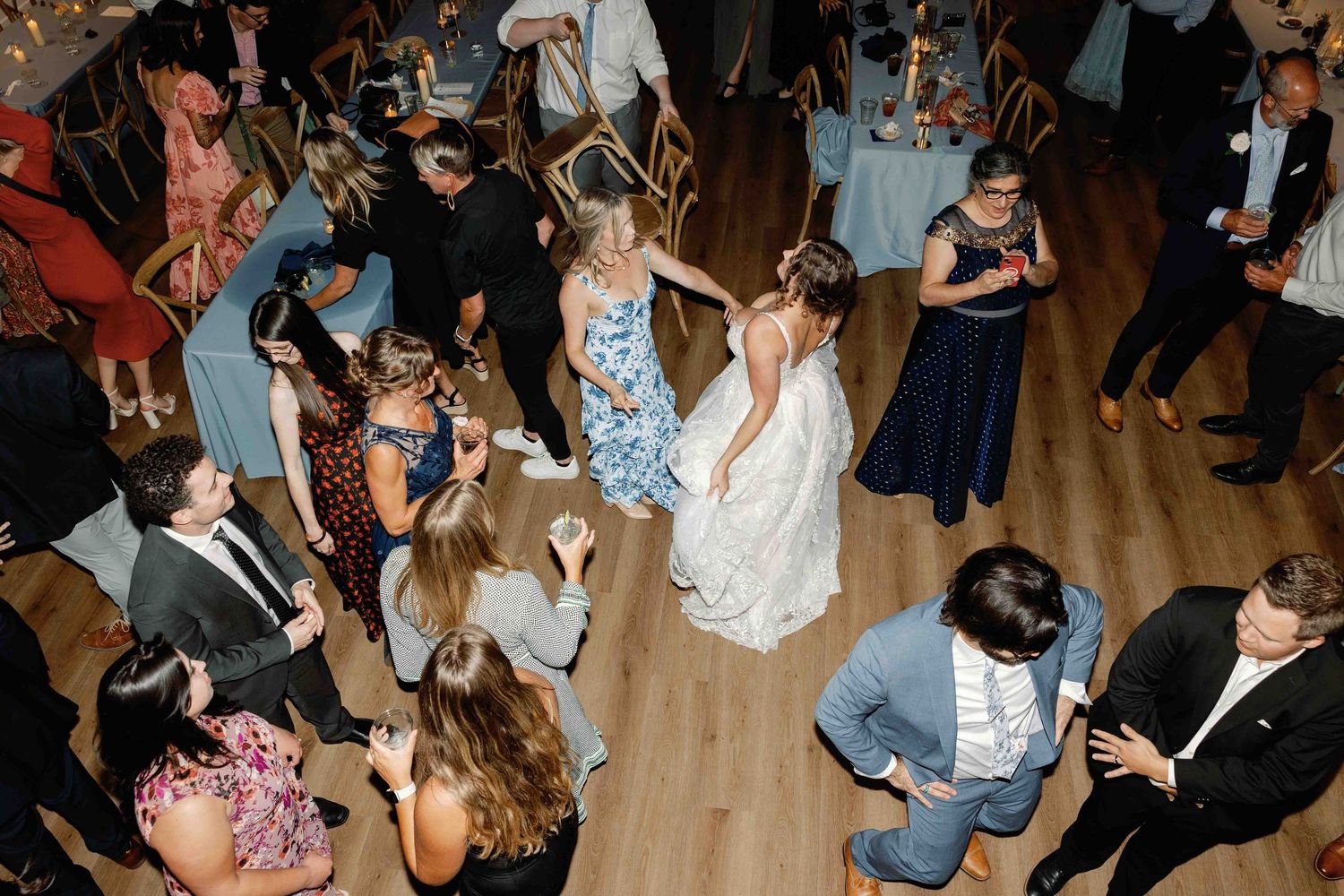 An overhead view of a lively wedding reception dance floor with guests celebrating.
