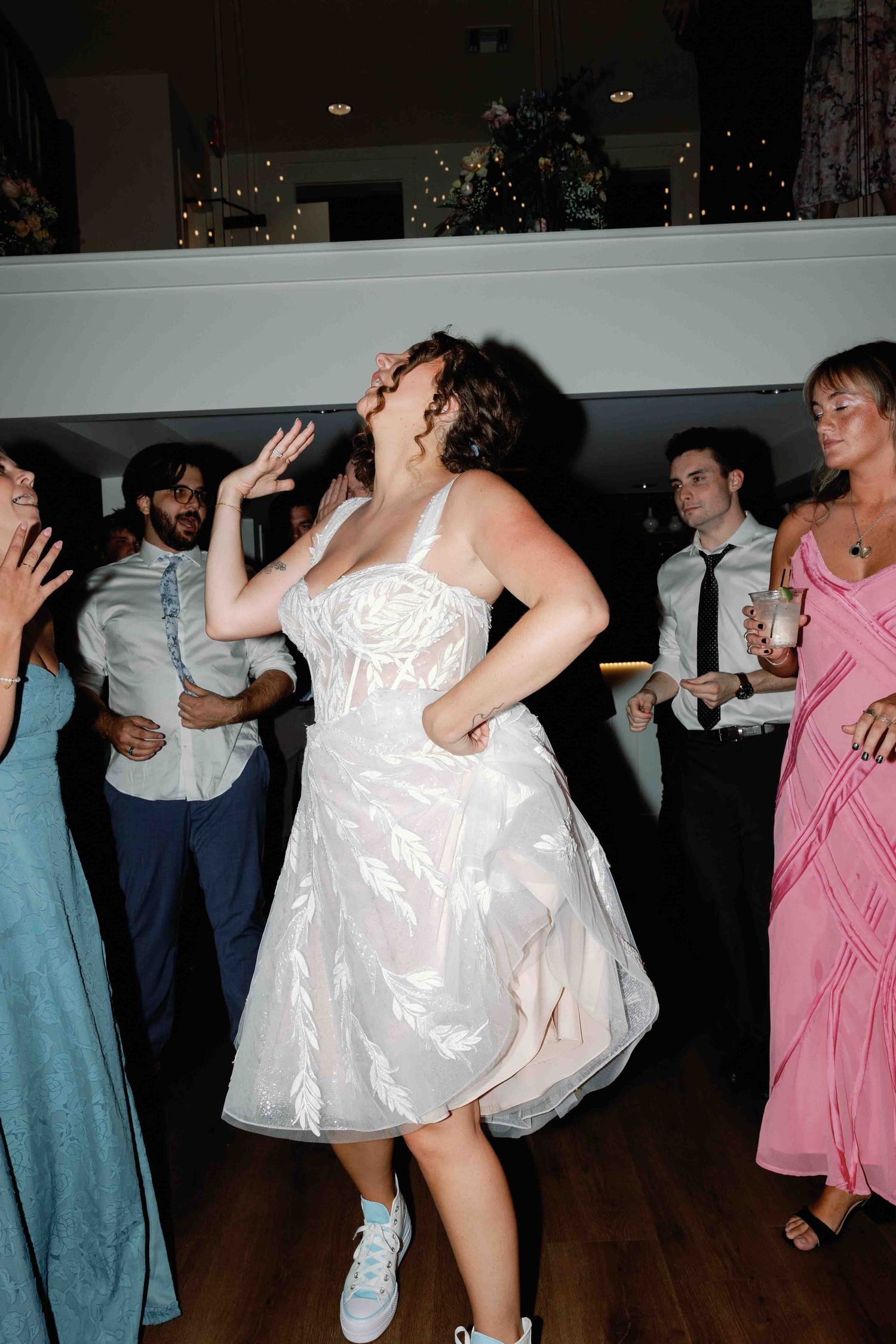 People dancing and celebrating at a wedding reception with colorful dresses.