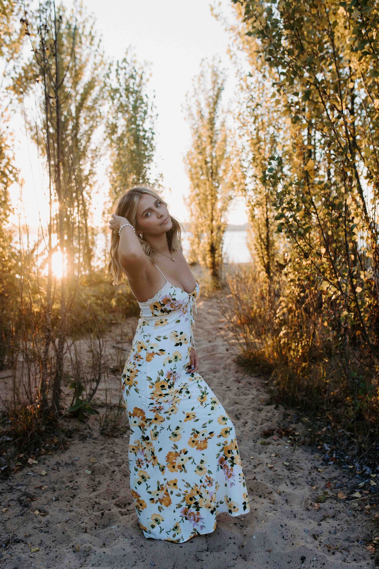 A floral sundress photoshoot against a backdrop of golden sunset light and tall trees.