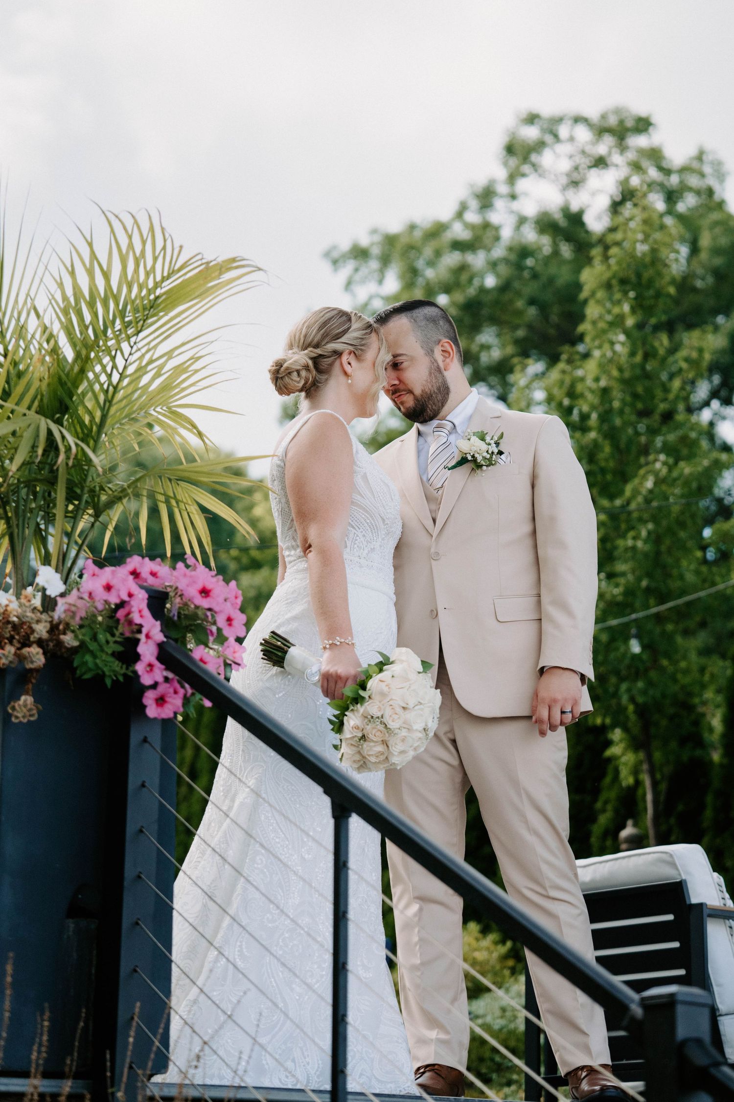 Romantic wedding moment on a deck decorated with pink flowers and tropical plants.