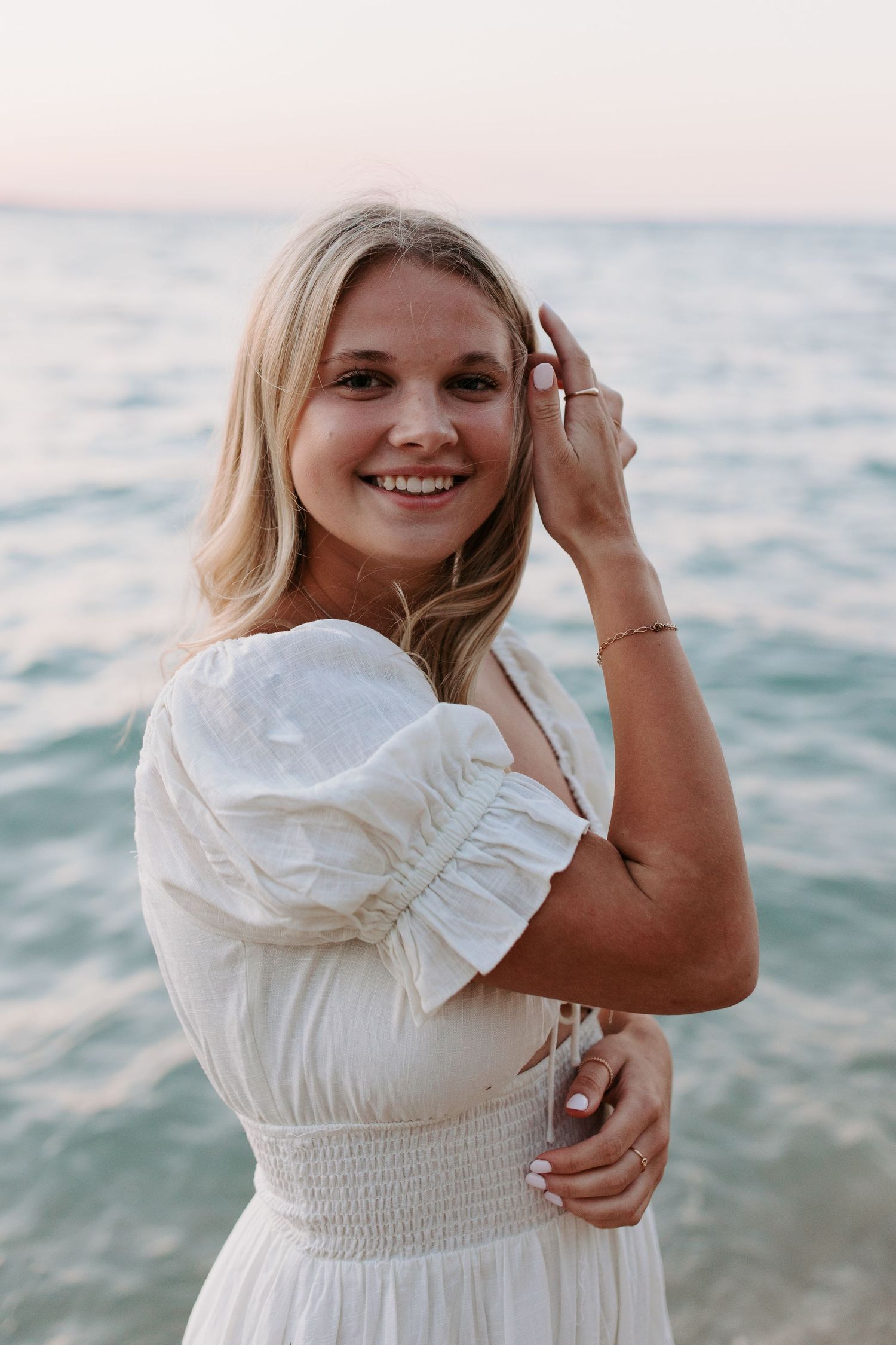 White summer dress photographed against ocean backdrop during sunset.