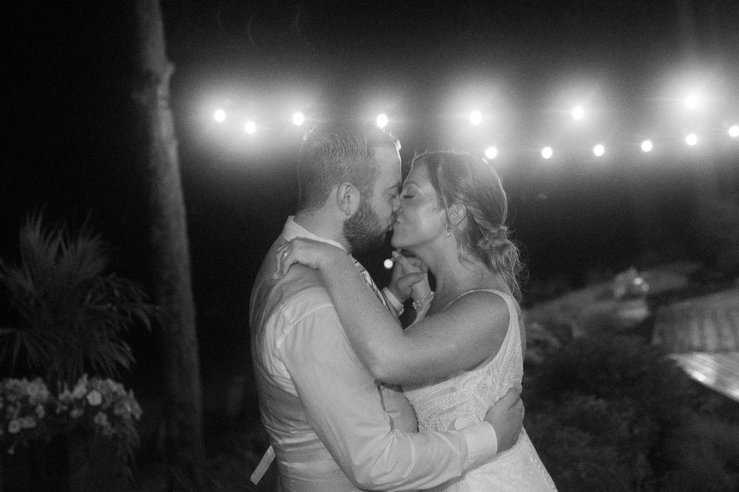 A romantic evening dance under string lights at an outdoor wedding reception.