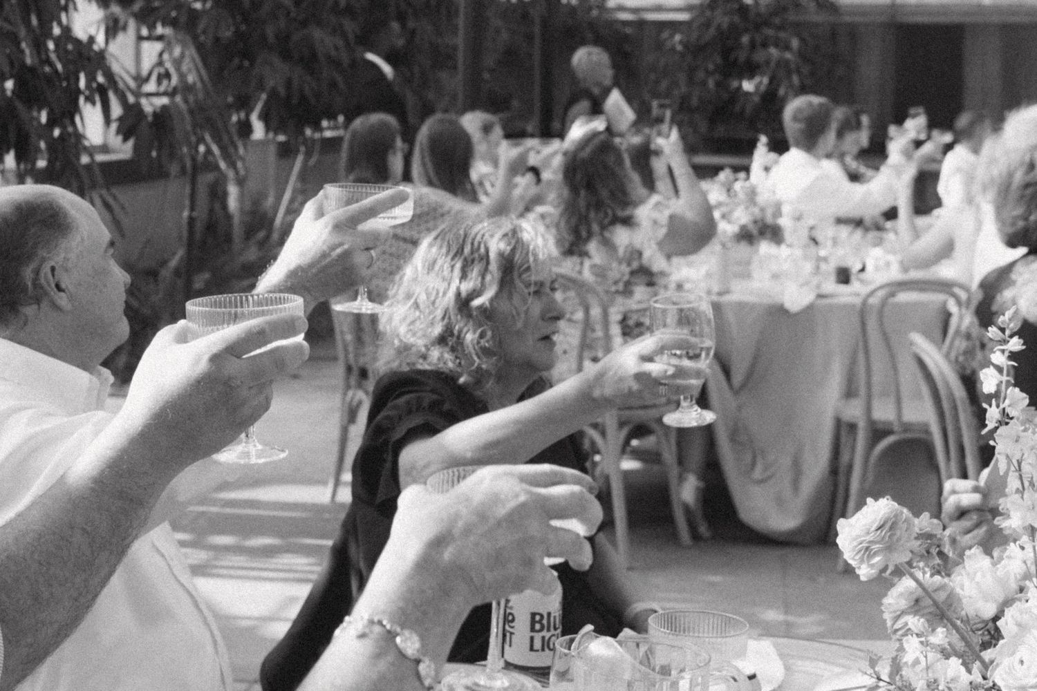 Black and white reception scene showing guests celebrating at tables.