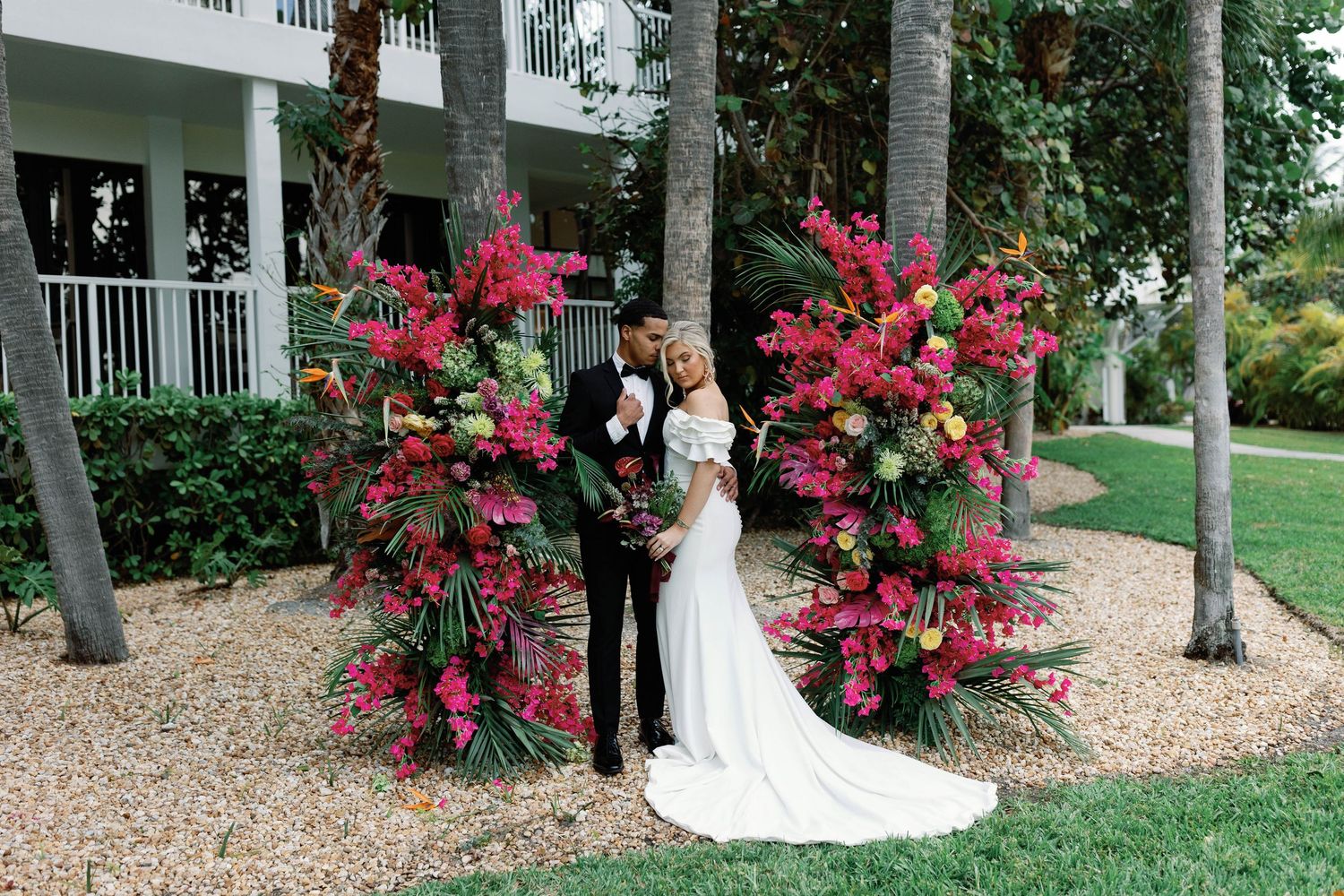 Wedding venue exterior with vibrant pink bougainvillea flowers and white columns creating an elegant backdrop.