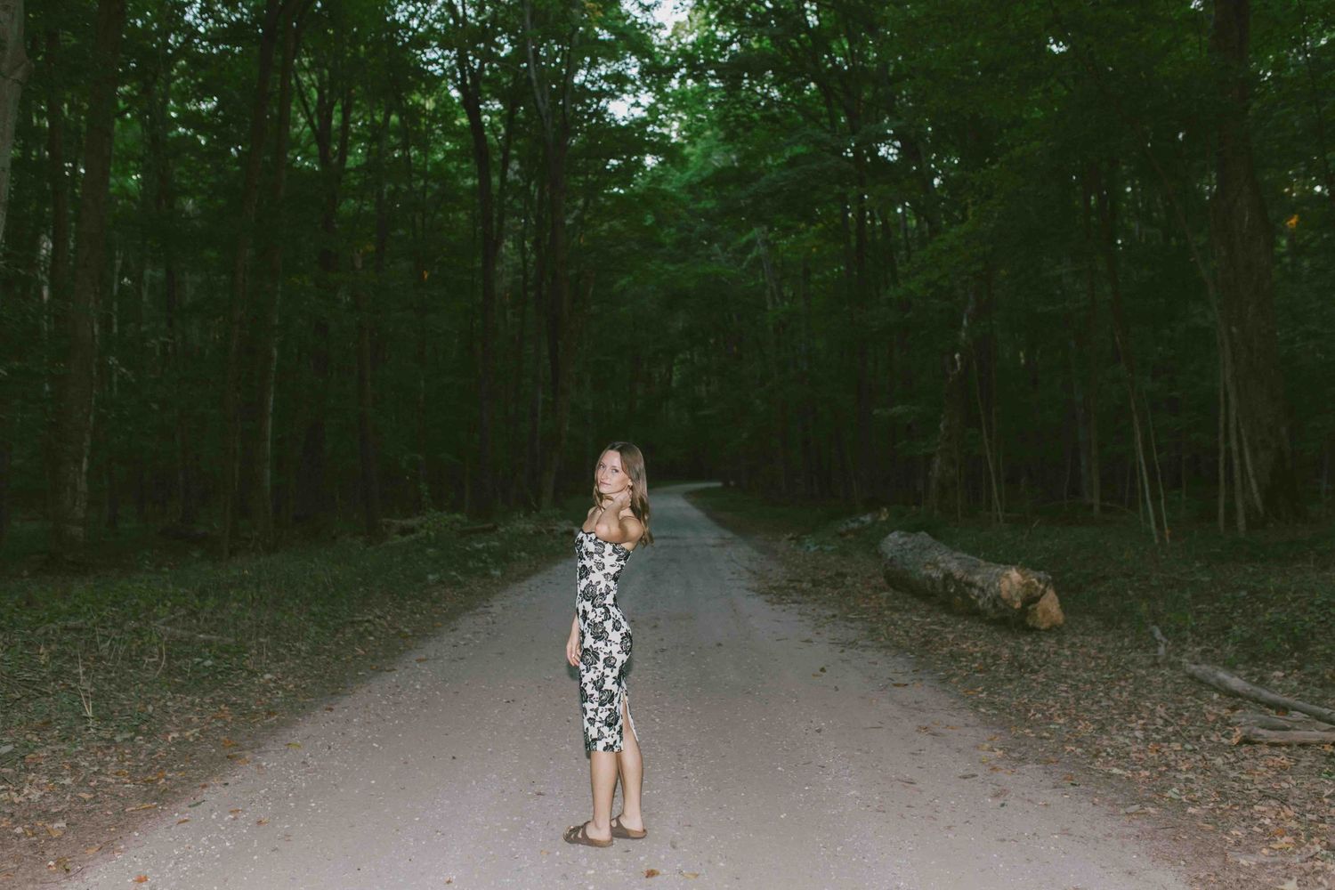Dark wooded path creates moody atmosphere for outdoor portrait session.