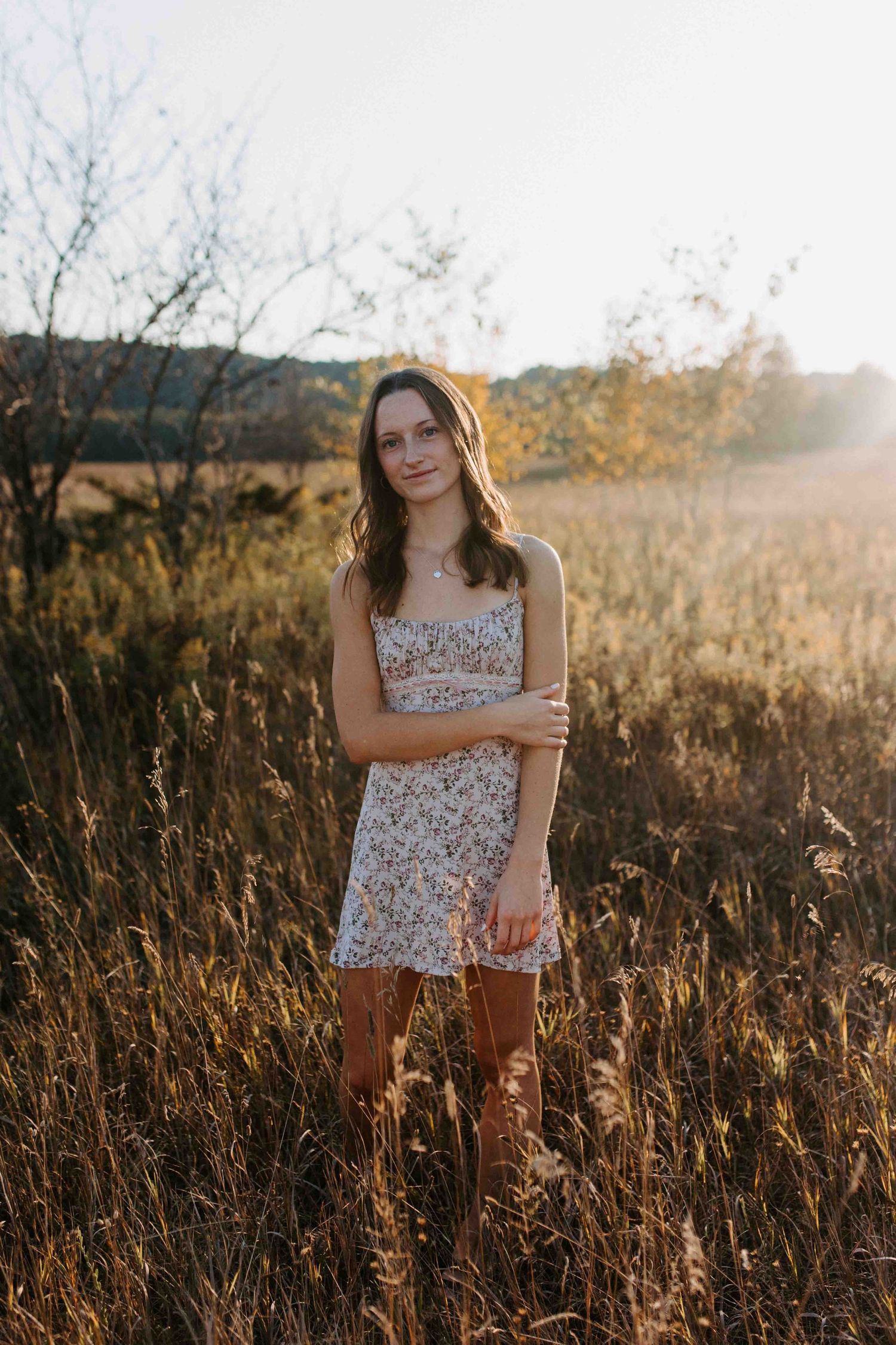 Golden hour portrait session in a wild grass field wearing a floral summer dress.