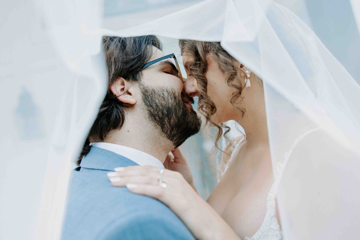 Intimate close-up shots of a couple sharing tender moments under a wedding veil.