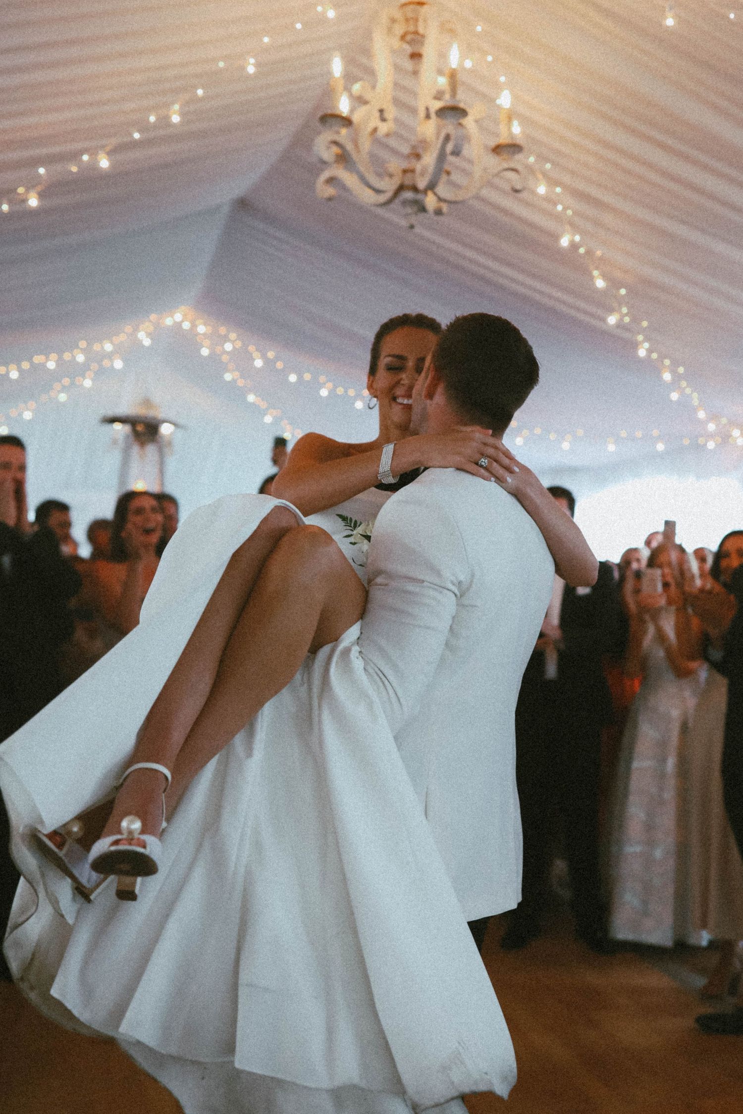 First dance moment under twinkling lights in an elegant white tent reception.