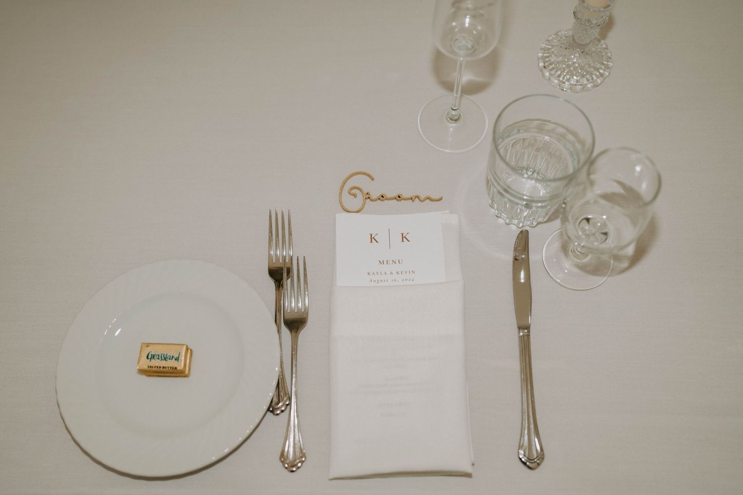 Close-up of formal place settings with silverware and white plates at a wedding reception.