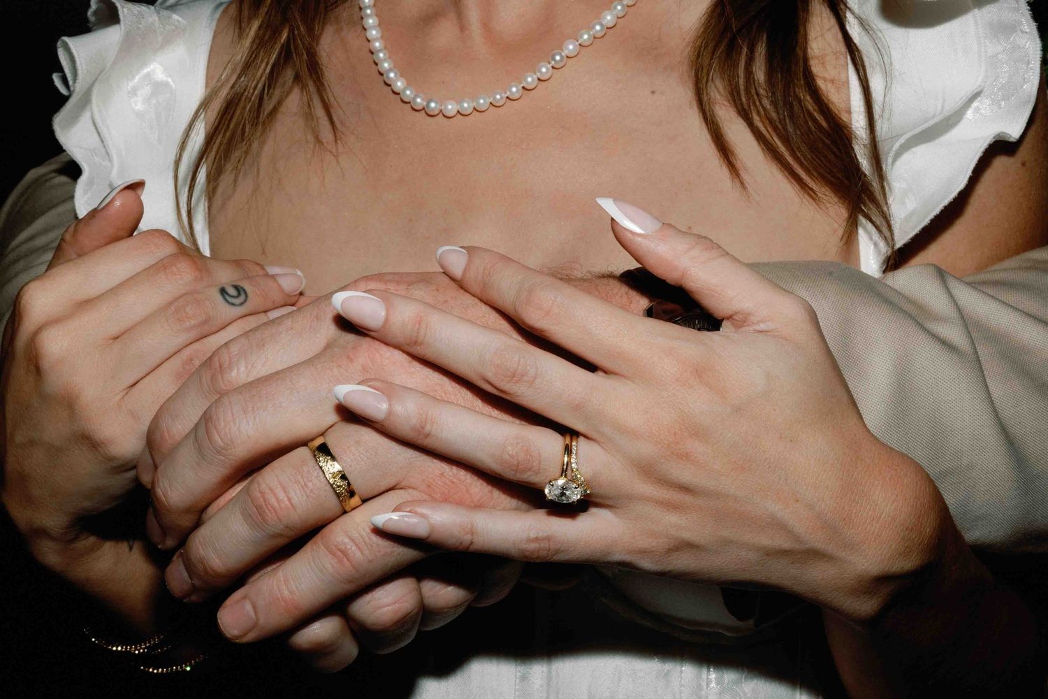 Close-up shots of hands wearing wedding rings and pearl jewelry.
