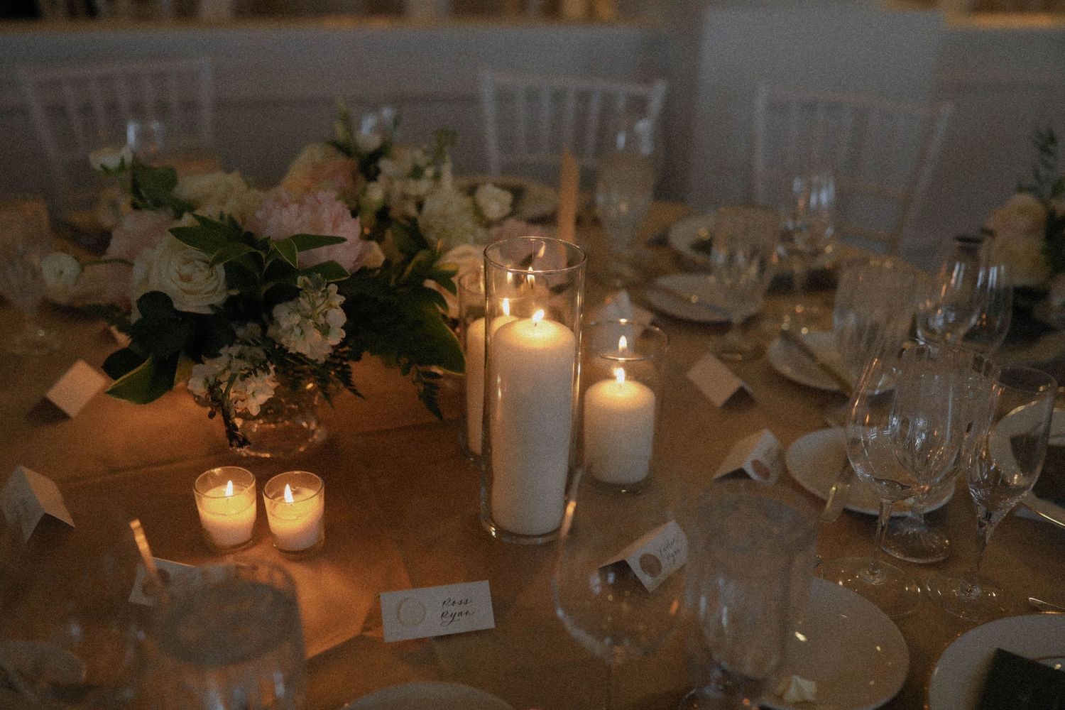 Elegant wedding reception table settings with glowing candles and floral centerpieces.