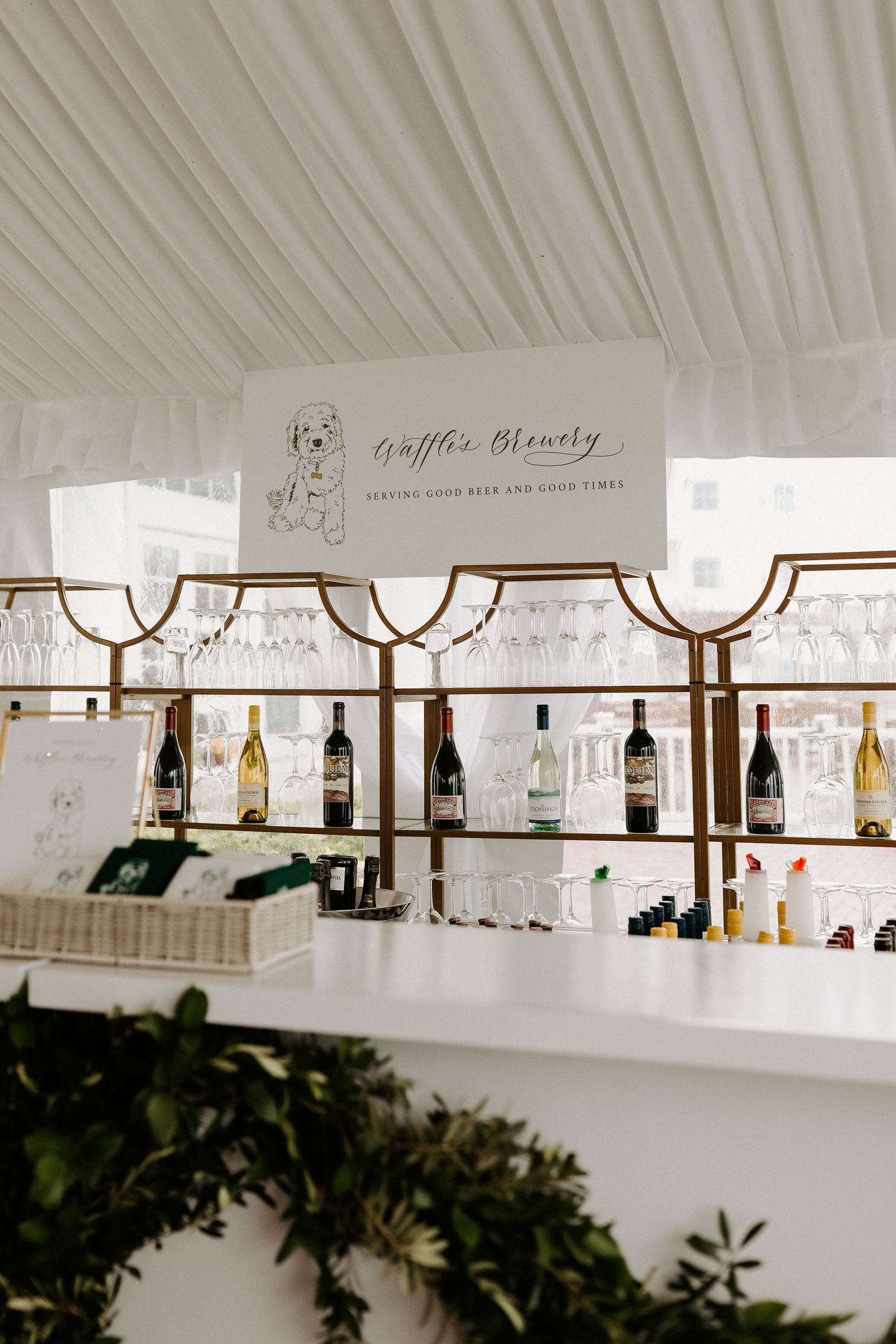 A wedding bar setup with illuminated shelving displaying various bottles of wine and spirits.