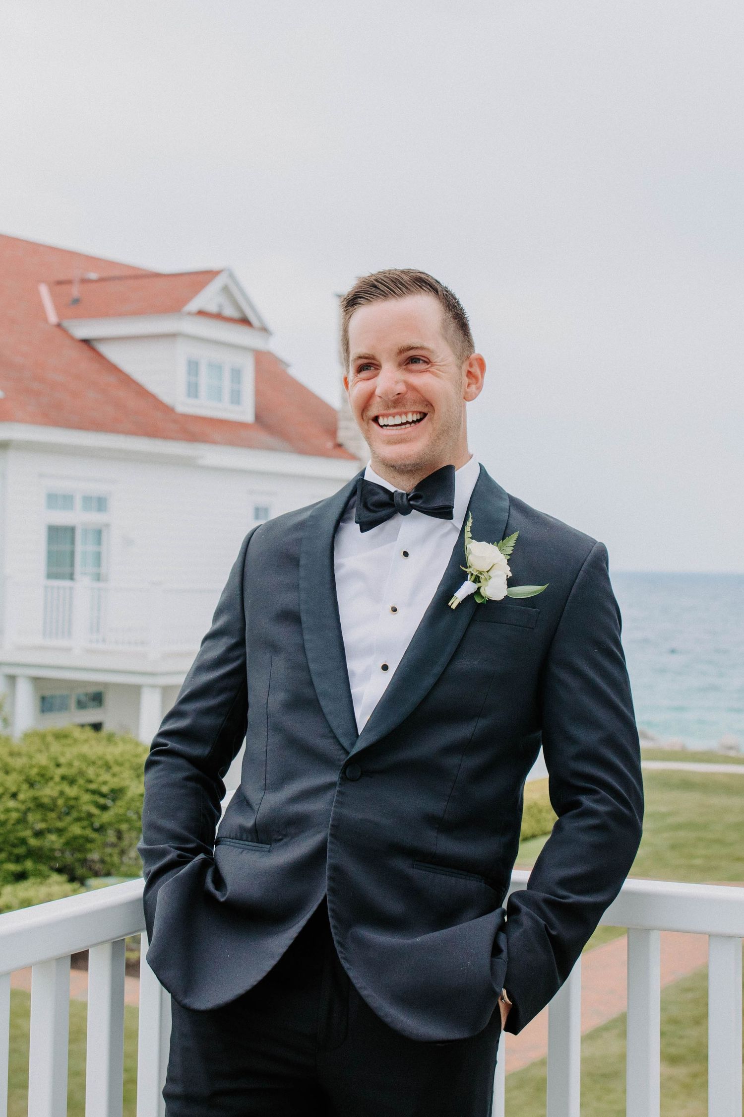 Elegant tuxedo and boutonniere against coastal wedding venue backdrop.