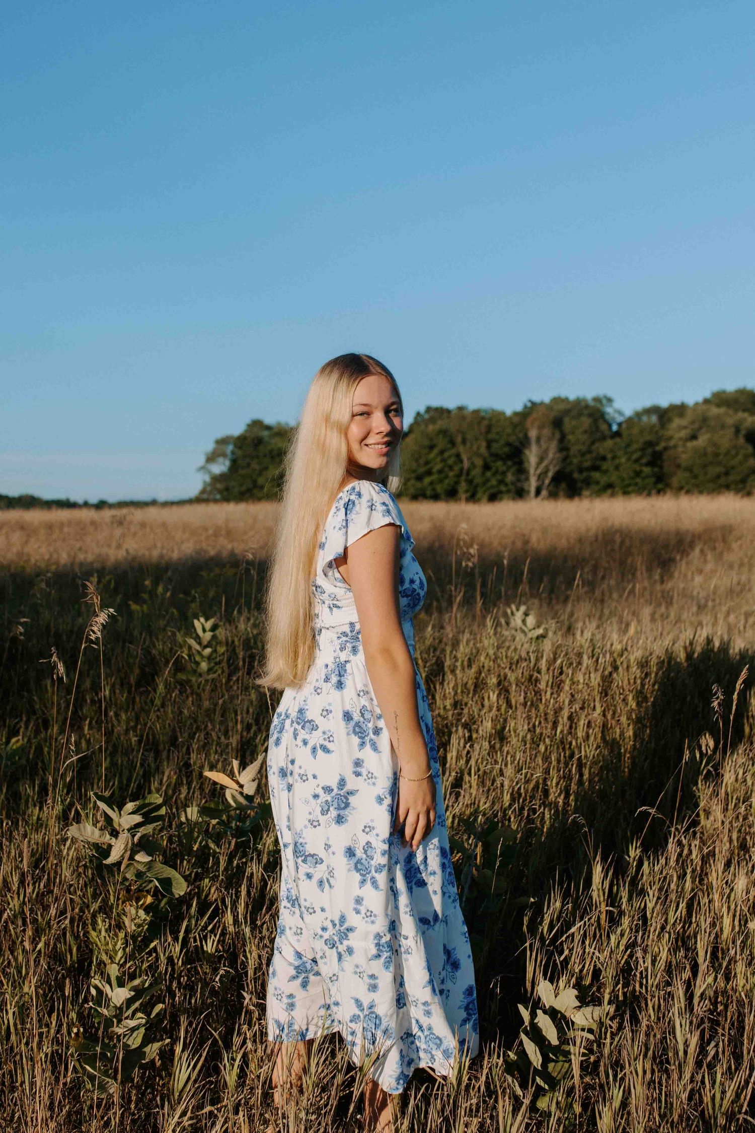 Carefree moment captured in a summer field wearing a floral dress.