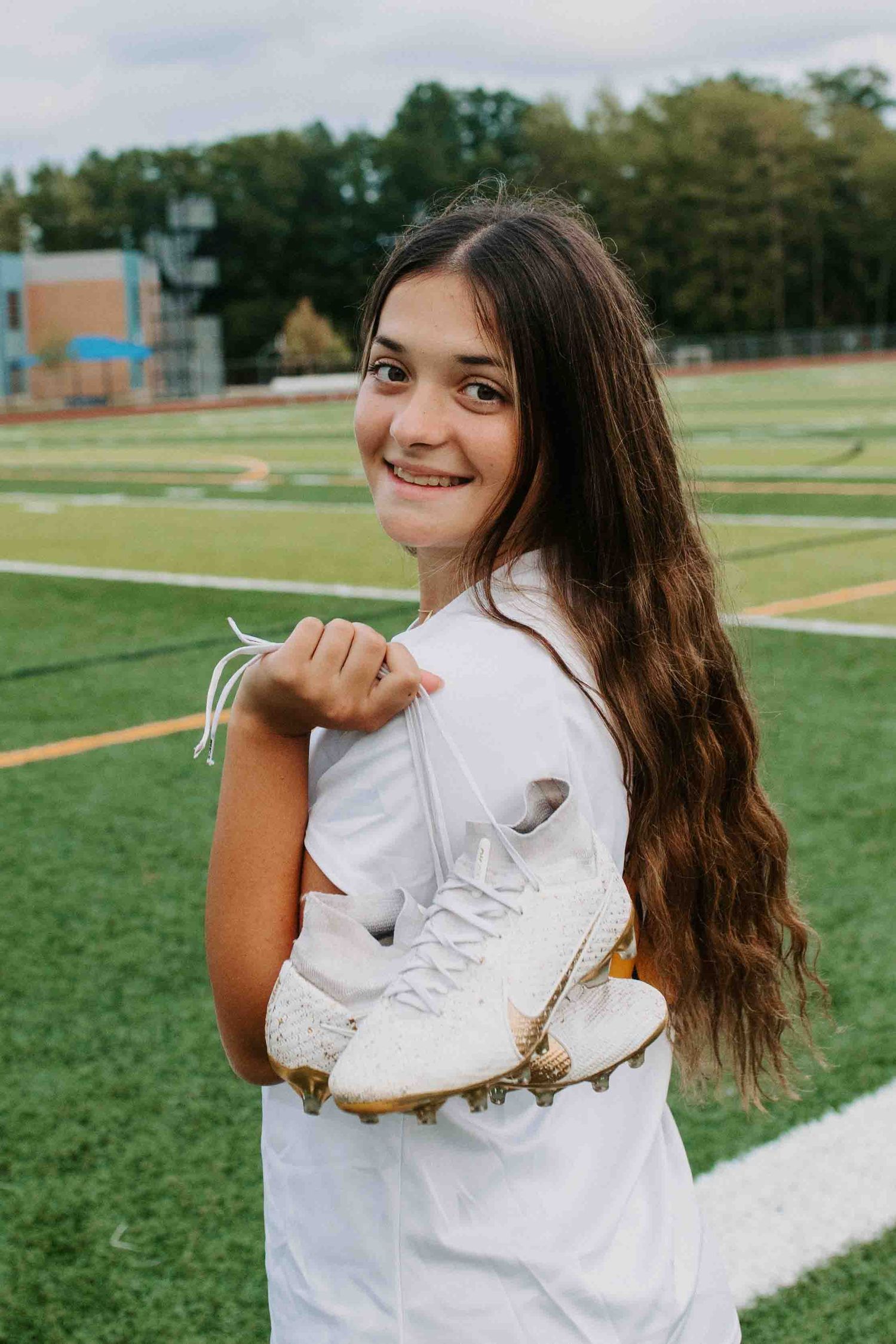 Soccer player showing off white cleats on athletic field.