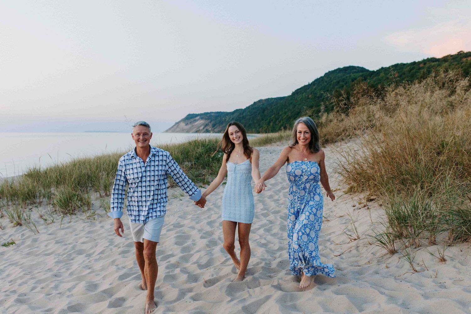 Group walking together along a scenic beach path with sand dunes and ocean views.