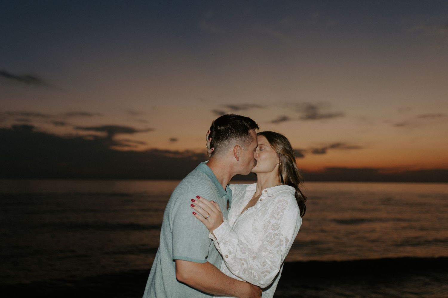A romantic silhouette of a couple against a dramatic sunset over the ocean.