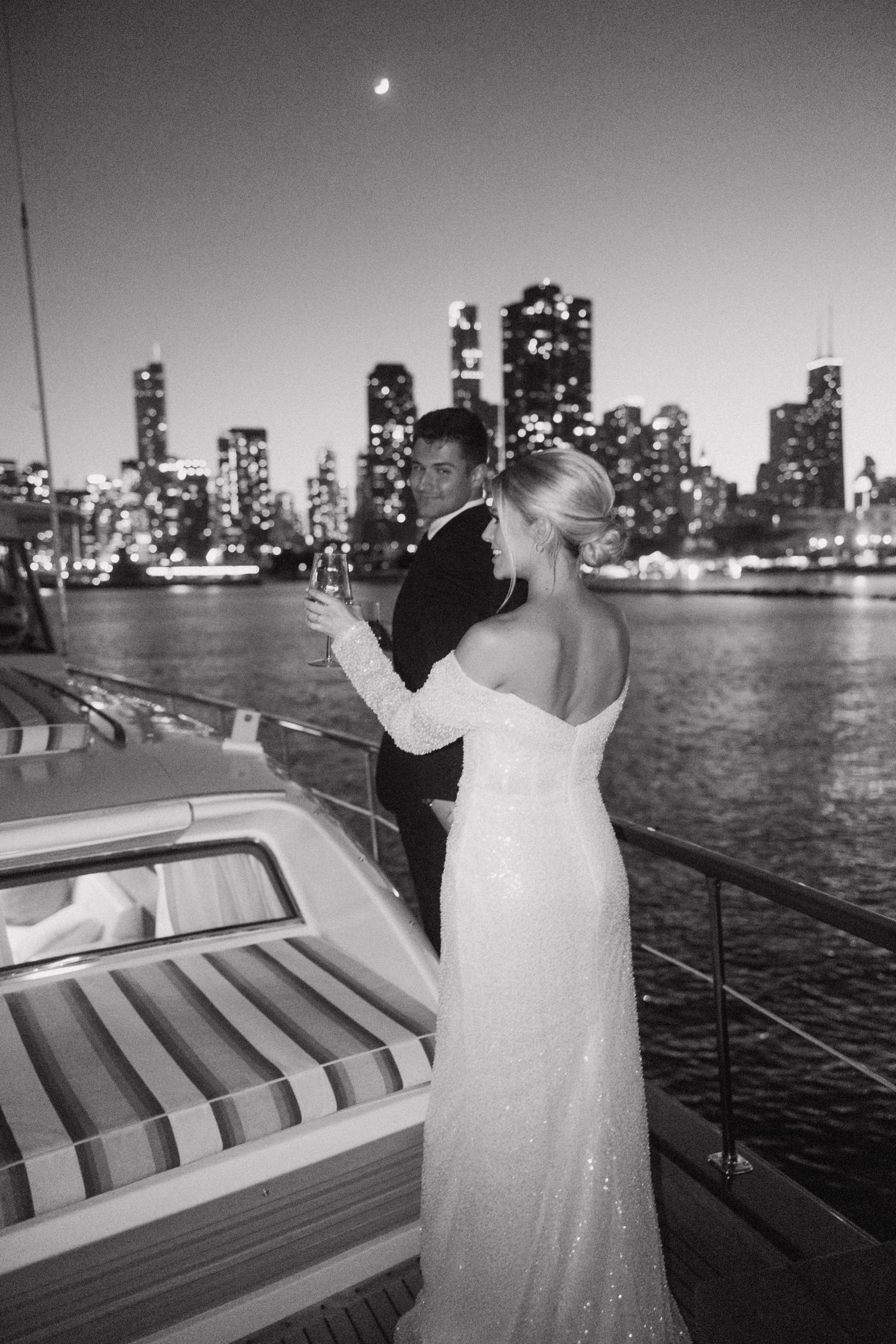 Black and white boat wedding photos with illuminated city skyline in background.