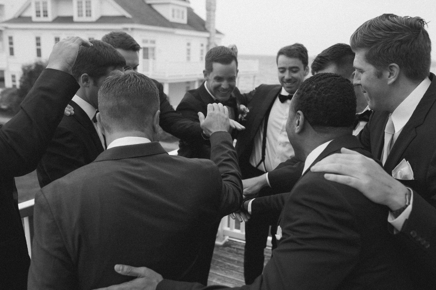 A group in formal attire gathers at an elegant white building for a celebration.