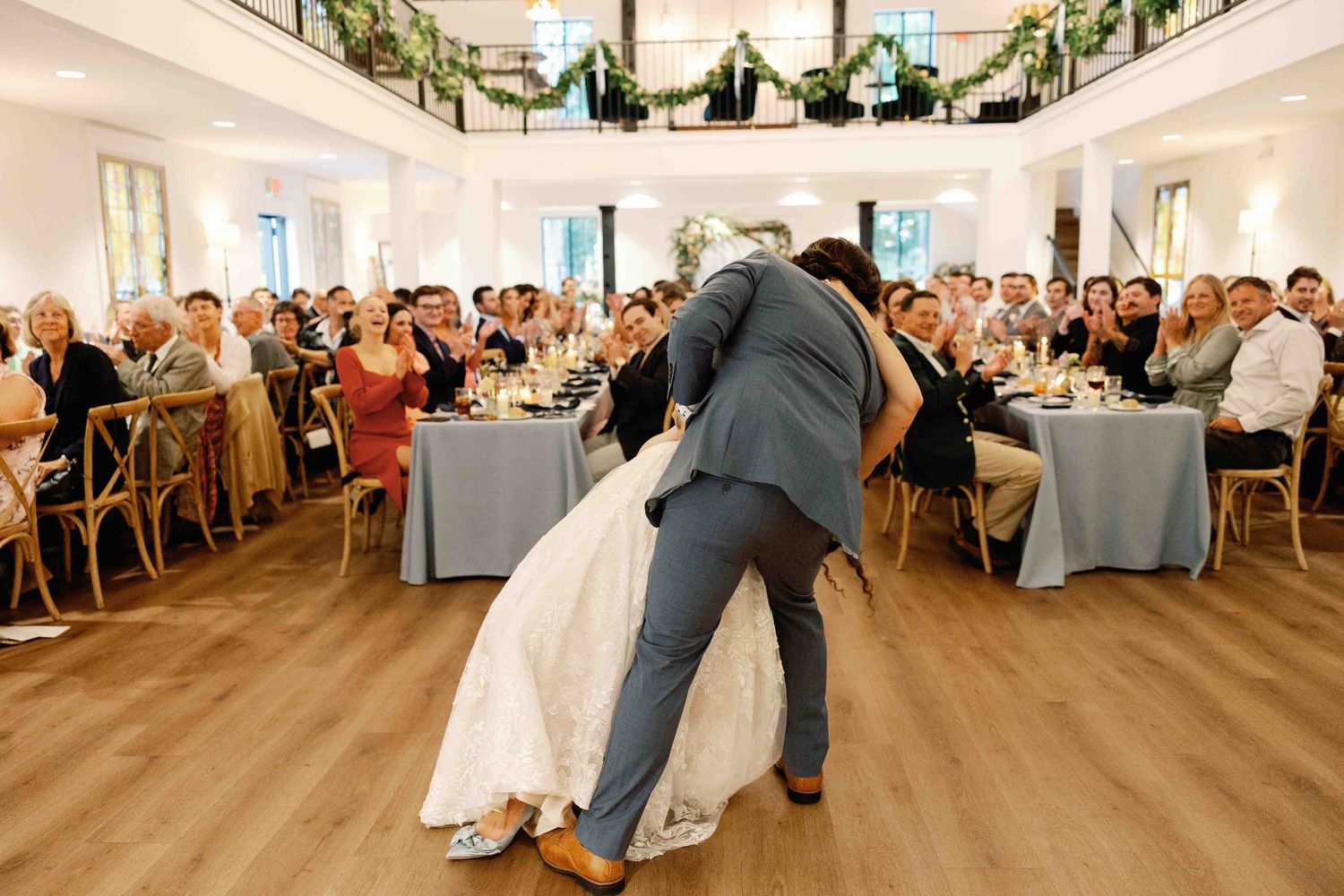 Wide view of a wedding reception hall with guests watching a dance performance.