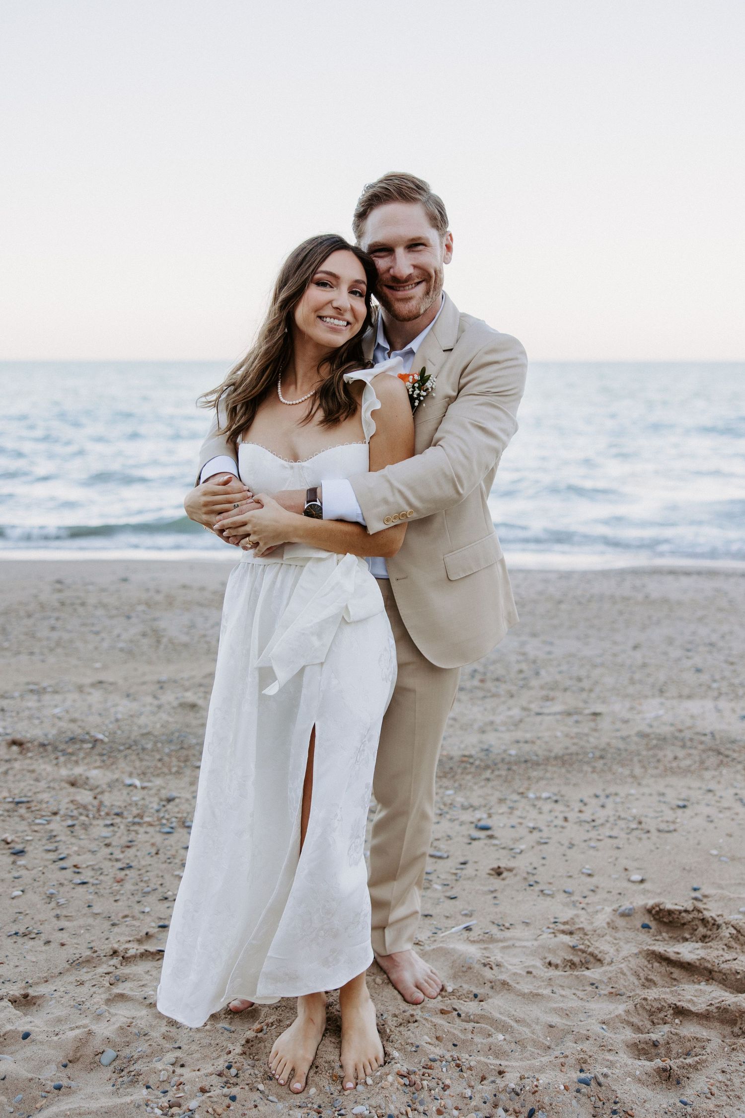 Happy couple sharing intimate moments during beach wedding photoshoot with ocean backdrop.