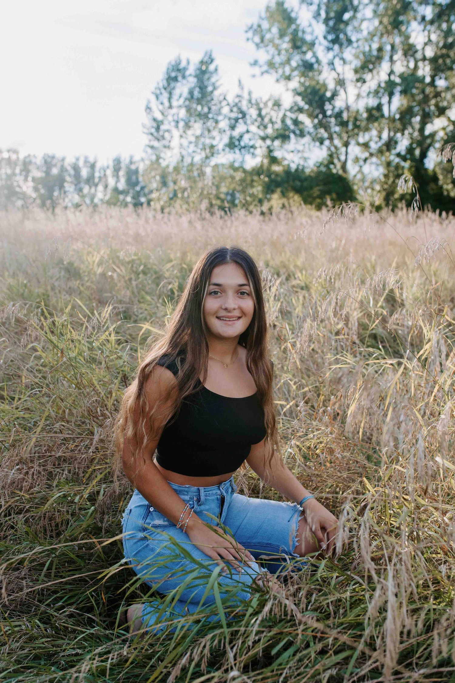 Relaxed outdoor portrait session in tall grass during golden hour.