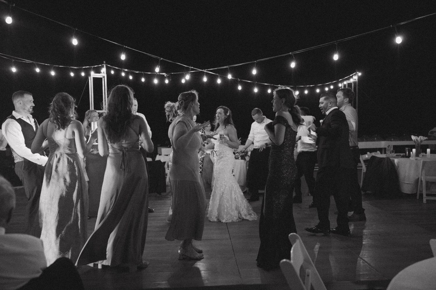 String lights illuminate an outdoor evening wedding reception space.