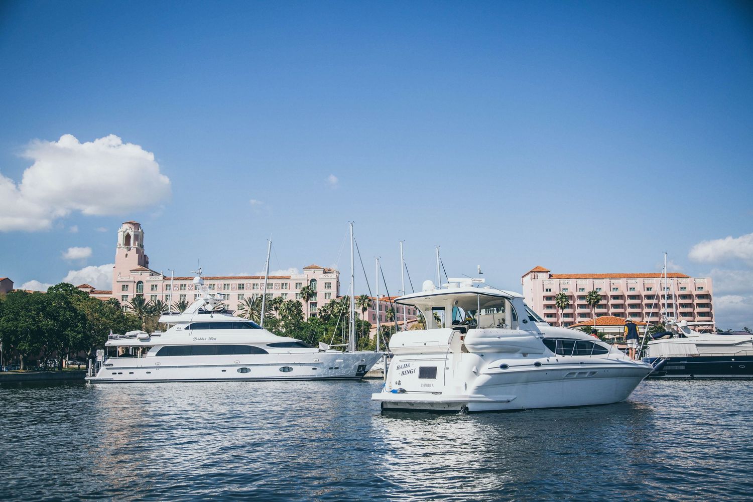 Luxury yachts docked at a marina with historic buildings and palm trees along the waterfront in Charleston, South Carolina.